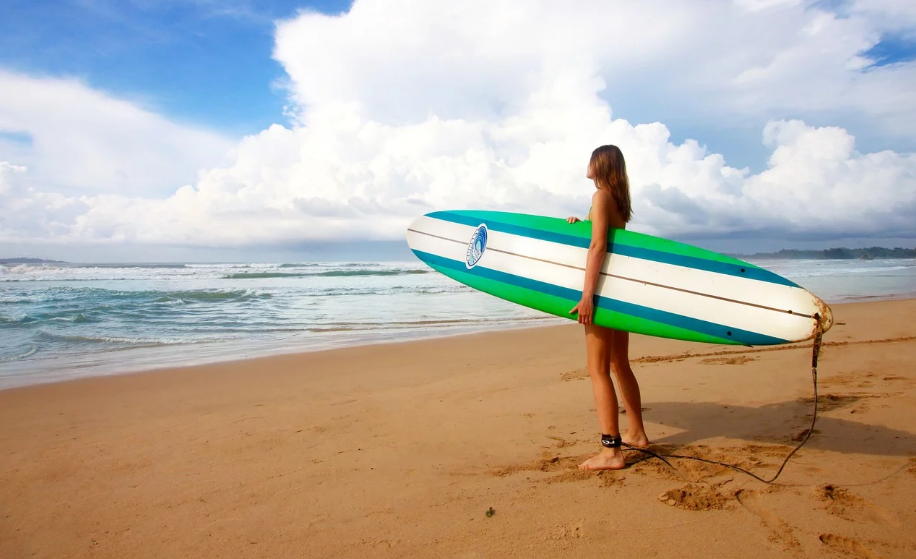 Kvinde på strand med surfboard