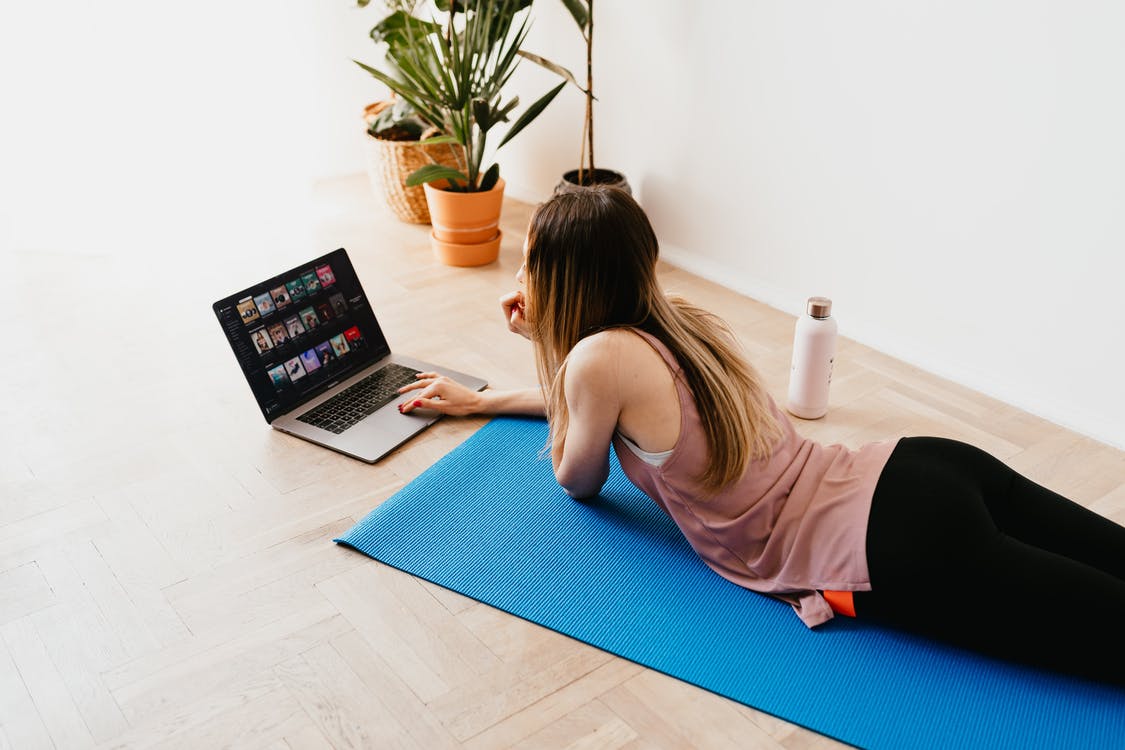 Liggende kvinde på yogamåtte med computer